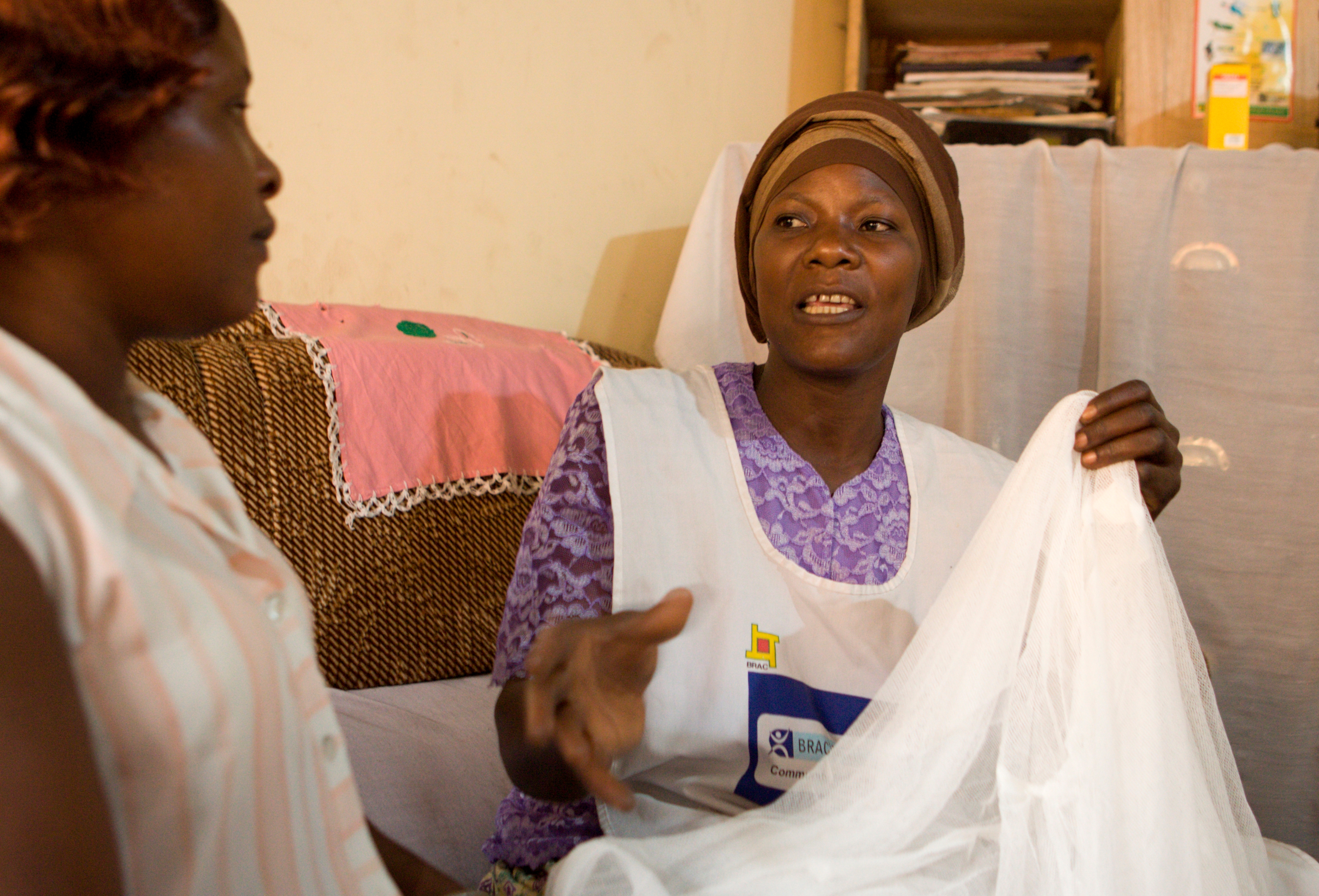 BRAC Uganda Community Health Promoter Gertrude Kahanda demonstrates the use of a mosquito net with patient Farida Muzafaru